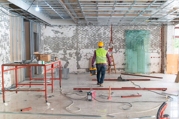 Rakentaja työskentelee yhtenäinen suojakypärä seisoo välineitä työmaalla sisätiloissa - Valokuva, kuva