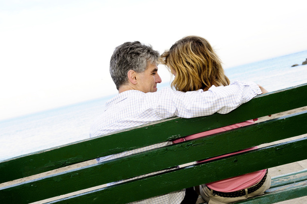Mature romantic couple on a bench on seashore - Foto, imagen