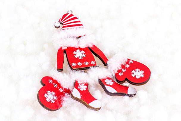 Byt ležel jasně červené vánoční Santa Claus oblečení na bílém umělém sněhu pozadí s kopírovacím prostorem. Vánoce a Silvestrovské svátky koncepce oslav. - Fotografie, Obrázek