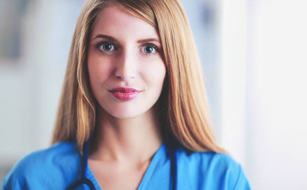 Portrait of woman doctor with folder at hospital corridor - Zdjęcie, obraz