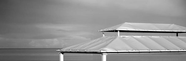Вид с зонтика на морской пляж. Морской пейзаж с голубым небом и морской водой. Beach Umbrellas Or Sunshade Top. Навес, навес, деталь палатки. - Фото, изображение