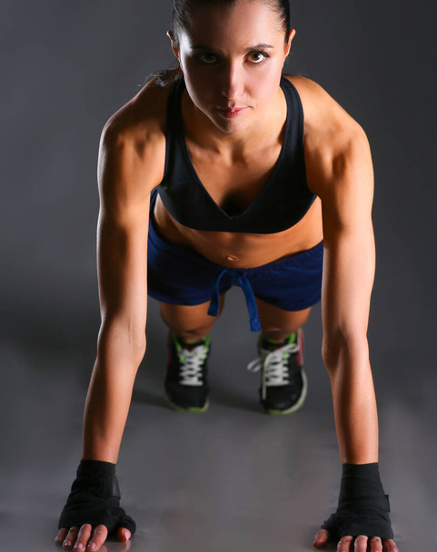 Young woman doing push ups on a mat - Фото, изображение