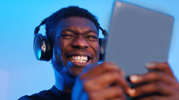 Afričtí američtí černošky muž se sluchátky dělat intenzivní výraz obličeje při použití tablet - Fotografie, Obrázek