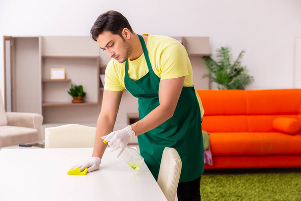 Joven contratista masculino limpiando la casa en interiores - Foto, Imagen