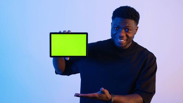 Hombre mostrando una tableta con una pantalla verde en la cámara - Gestos de mano - Foto, imagen