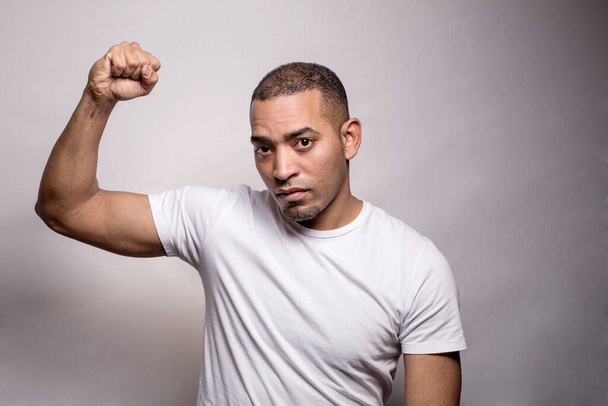 A portrait of Hispanic man with the raised fist, isolated on the grey background - Photo, Image