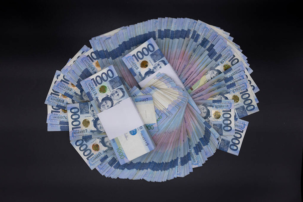 フィリピンの1,000枚の紙幣の山。現金千ドル札、ペソの背景画像. - 写真・画像