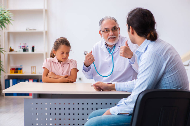 Small girl with her father visiting old male doctor - Photo, image