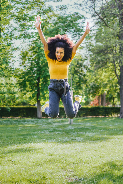 Jolie femme sautant joyeusement dans un jardin. Corps entier. - Photo, image