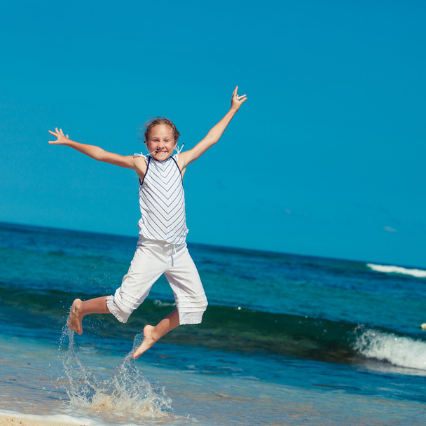 夏のボカで青い海岸浜にジャンプの十代の少女 - 写真・画像