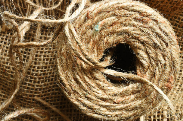 Un'immagine ravvicinata di bobine di corda di iuta beige su tessuto di iuta.  - Foto, immagini