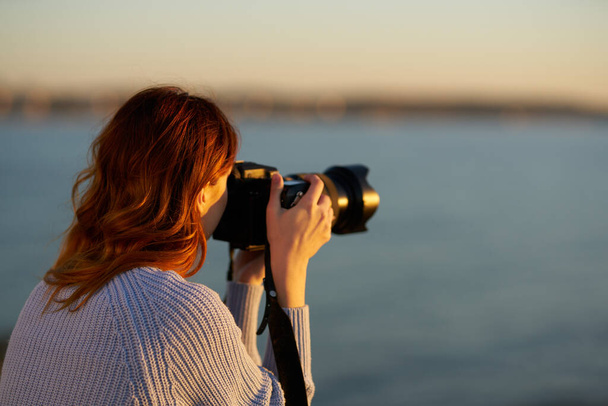 žena s profesionální kamerou při západu slunce u moře - Fotografie, Obrázek