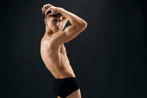 handsome athletic man in dark shorts muscles dark background - Foto, Imagem