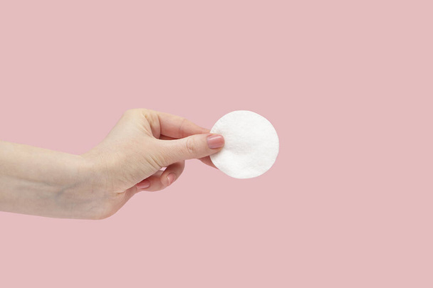 Cotton pad in a female hand on a pink background. - Photo, Image