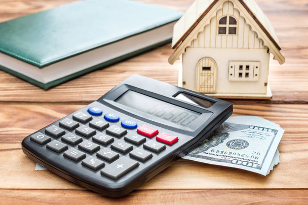 Modèle de maison avec calculatrice, argent et bloc-notes sur la table.  - Photo, image