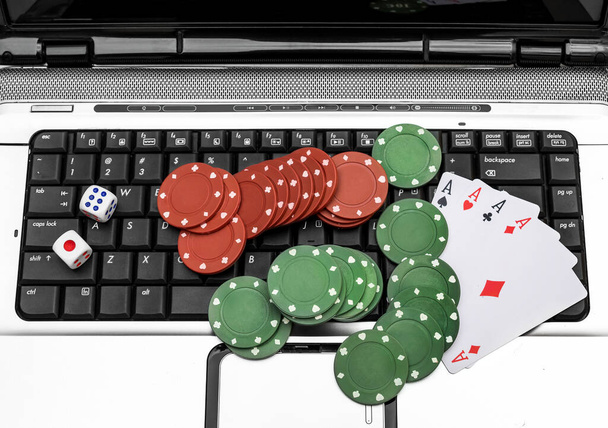 Παίζοντας χαρτιά με μάρκες πόκερ και ζάρια στο πληκτρολόγιο laptop. Online καζίνο. - Φωτογραφία, εικόνα