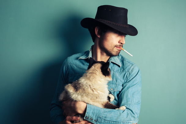 Young cowboy with cat is smoking - Foto, immagini