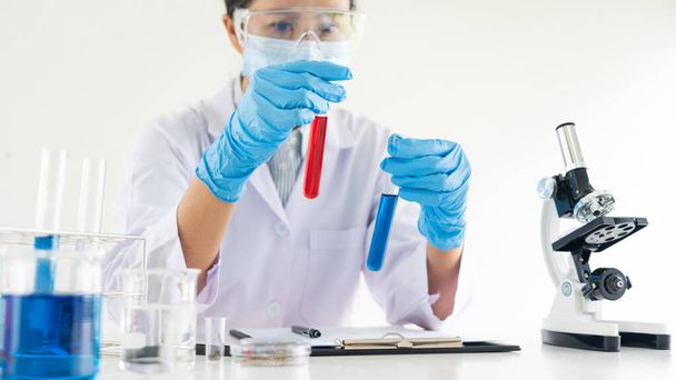 Wissenschaftler forschen im Labor im weißen Laborkittel, Handschuhe analysieren, Reagenzglasprobe betrachten, Biotechnologie-Konzept. - Foto, Bild