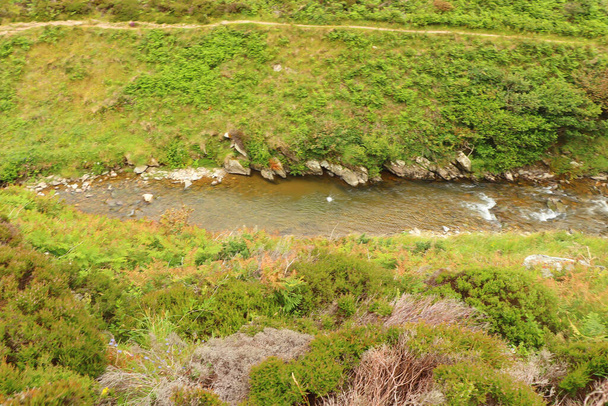 Rio Heddon fluindo através do vale e sobre terreno rochoso - Foto, Imagem