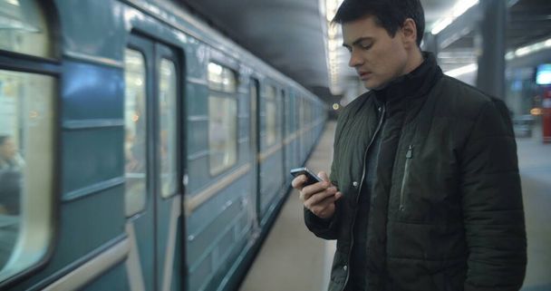 Man typing sms standing on the subway platform - Photo, Image