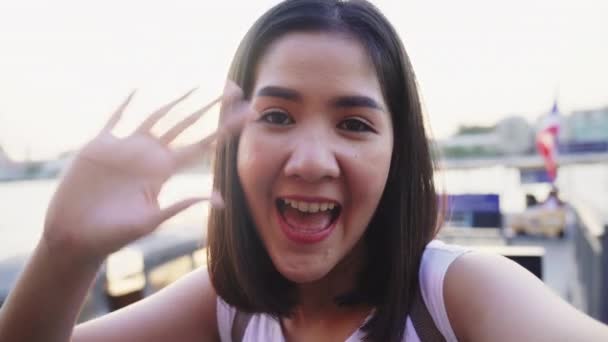 Счастливая молодая азиатская женщина-блоггер турист с случайным стиль глядя на камеру принять селфи видео звонок пользоваться с красивым закатом реки зрения кафе в городе, стиль жизни туристических поездок. - Кадры, видео