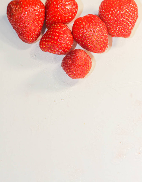 Una gran cantidad de fresas rojas maduras y sabrosas yacen sobre un fondo blanco - Foto, Imagen