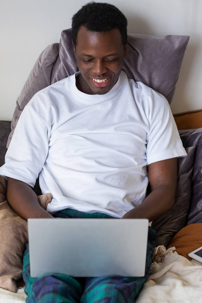 Hombre africano navegando por Internet en su cama en casa - Foto, Imagen