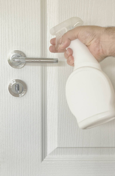 Чоловік чистить і дезінфікує двері обробляє щоденний антибактеріальний захист від коронавірусу
 - Фото, зображення