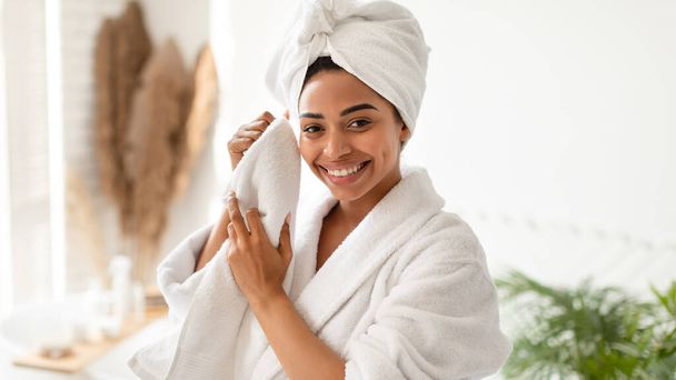 バスルームでタオルで顔を乾かす幸せなアフリカ系アメリカ人女性 - 写真・画像