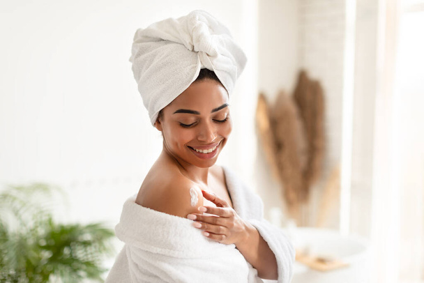 Afro-Américaine Lady hydratant la peau avec la lotion debout dans la salle de bain - Photo, image