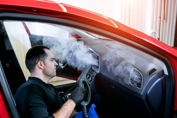 Car service worker cleans interiror with steam cleaner - Fotoğraf, Görsel