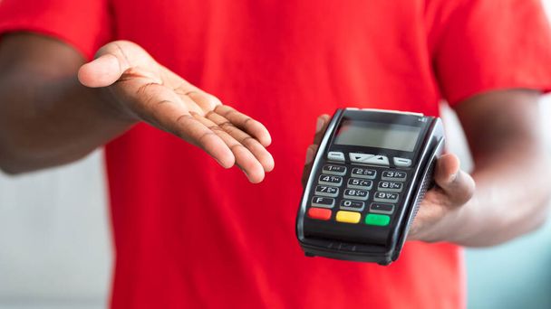 Cropped view of black man in uniform holding POS machine - Photo, Image