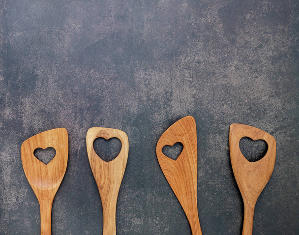 Various heart shape of wooden cooking utensils. Wooden spoons and wooden spatula on dark concrete background with flat lay and copy space. - Photo, Image