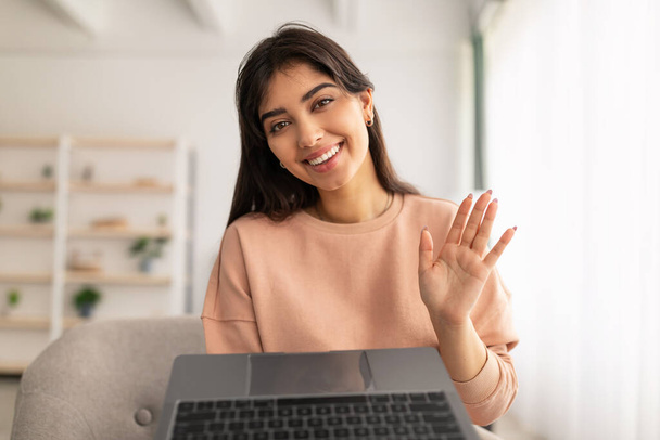 Mujer teniendo videollamada usando laptop y saludando - Foto, imagen