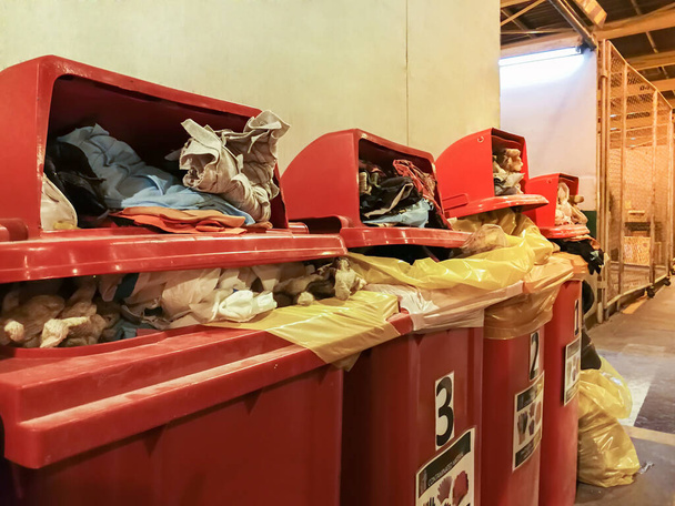 Trapo y guante usado algodón contaminado con aceite clasificado en cubo de basura rojo en la fábrica, contenedor completo de basura roja - Foto, imagen