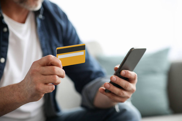 Nierozpoznawalny mężczyzna ze smartfonem z kartą kredytową - Zdjęcie, obraz
