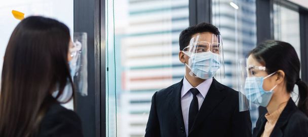 candid shot, close up man office worker wearing medical mask and face shield, business people meeting in corporate. - Photo, Image