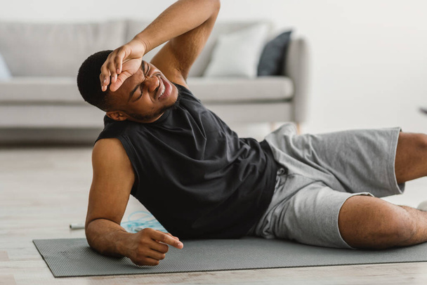 Афроамериканец чувствует себя плохо во время тренировки дома - Фото, изображение