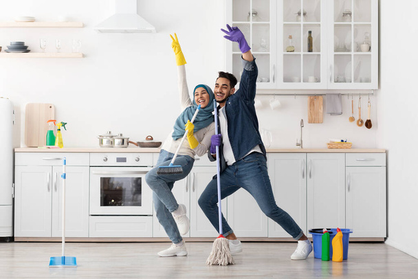 Забавная мусульманская пара поет песни во время уборки кухни, копировать пространство - Фото, изображение