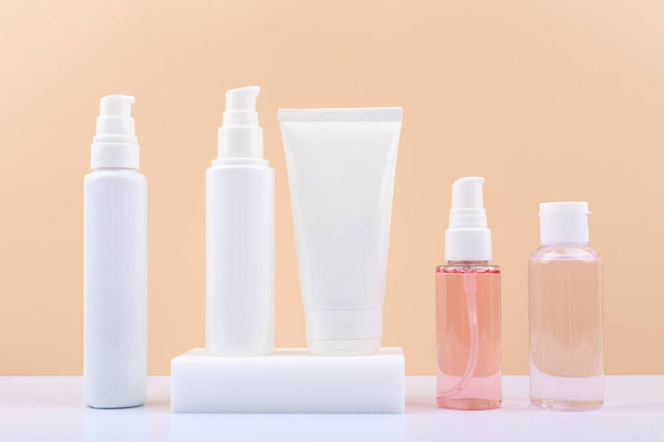 Set of cosmetic bottles for daily skin care routine on white table against light beige background.  - Фото, изображение