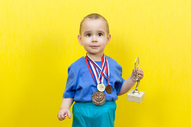 Little child dreams of sports victory, yellow background. - Photo, Image