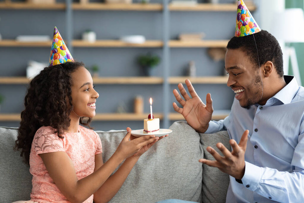 Beautiful black girl holding birthday cake for her excited dad - Zdjęcie, obraz