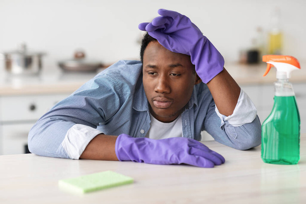 Tired black guy in gloves with spray bottle and sponge - Photo, image