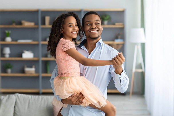 Молодий чорний тато навчає свою красиву дочку танцювати вальс
 - Фото, зображення