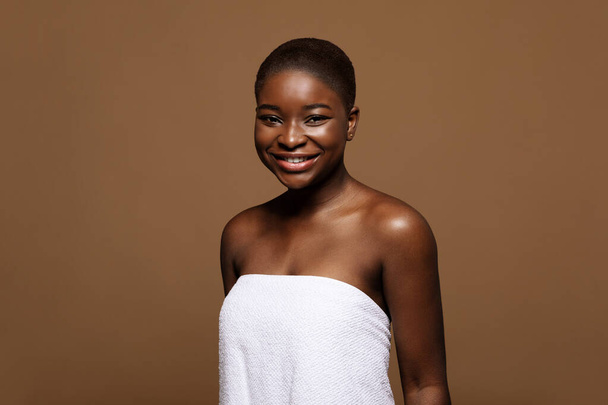 Портрет красивої афроамериканської жінки в рушничку ванни посміхається на камеру
 - Фото, зображення