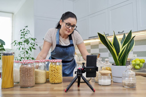 Online broadcast, blog about food, woman in an apron with jars of cereals - Foto, immagini