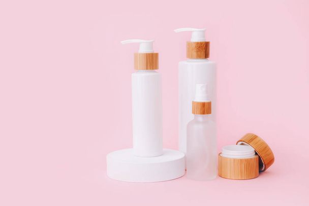 Productos cosméticos para el cuidado de la piel que permanecen en los podios geométricos. Presentación del producto sobre fondo rosa. - Foto, Imagen