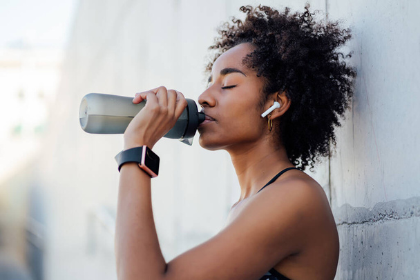 Athletic woman drinking water after work out outdoors. - Foto, Bild