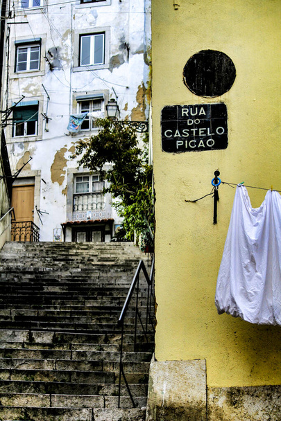 Στενά και πολύχρωμα δρομάκια με μεγαλοπρεπείς προσόψεις, παράθυρα και μπαλκόνια της πόλης της Λισαβόνας στην Πορτογαλία σε μια συννεφιασμένη ημέρα - Φωτογραφία, εικόνα