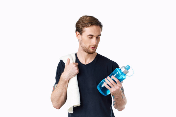 man in black t-shirt with bottle of water in hand and towel on shoulder cropped view - Fotoğraf, Görsel